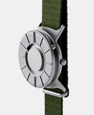 A photo of the watch from a side angle. The recessed track around the outside of the watch face is shown with the hour ball bearing in the track. The raised markers are noticeable from this perspective.