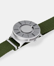 A photo of the watch lying flat on a surface. The recessed track around the outside of the watch face is shown with the hour ball bearing in the track. The raised markers are noticeable from this perspective.
