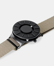 A photo of the watch lying flat on a surface. The recessed track around the outside of the watch face is shown with the hour ball bearing in the track. The raised markers are noticeable from this perspective.