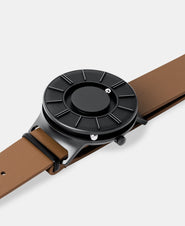 A photo of the watch lying flat on a surface. The recessed track around the outside of the watch face is shown with the hour ball bearing in the track. The raised markers are noticeable from this perspective.