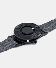 A photo of the watch lying flat on a surface. The recessed track around the outside of the watch face is shown with the hour ball bearing in the track. The raised markers are noticeable from this perspective.