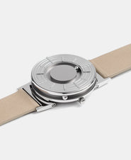 A photo of the watch lying flat on a surface. The recessed track around the outside of the watch face is shown with the hour ball bearing in the track. The raised markers are noticeable from this perspective.