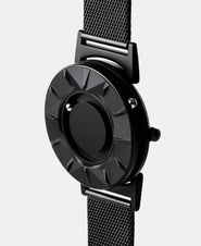 A photo of the watch from a side angle. The recessed track around the outside of the watch face is shown with the hour ball bearing in the track. The raised markers are noticeable from this perspective.