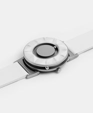 A photo of the watch lying flat on a surface. The recessed track around the outside of the watch face is shown with the hour ball bearing in the track. The raised markers are noticeable from this perspective.