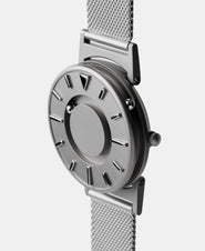 A photo of the watch from a side angle. The recessed track around the outside of the watch face is shown with the hour ball bearing in the track. The raised markers are noticeable from this perspective.