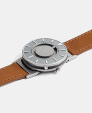 A photo of the watch lying flat on a surface. The recessed track around the outside of the watch face is shown with the hour ball bearing in the track. The raised markers are noticeable from this perspective.