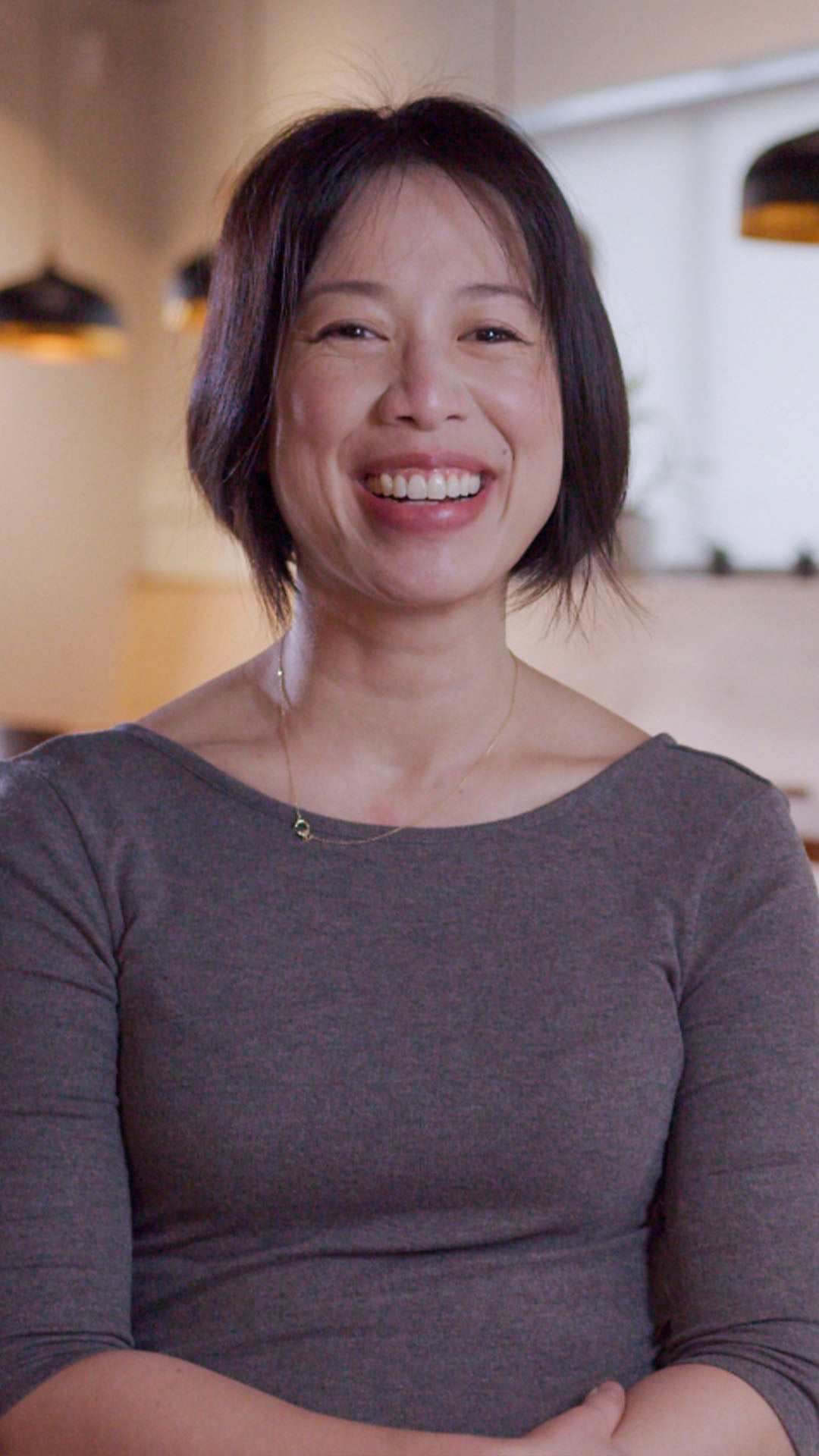 An image of Christine Ha. She is located in her restaurant, Xin Chao. She is smiling happily. Click play to watch video.