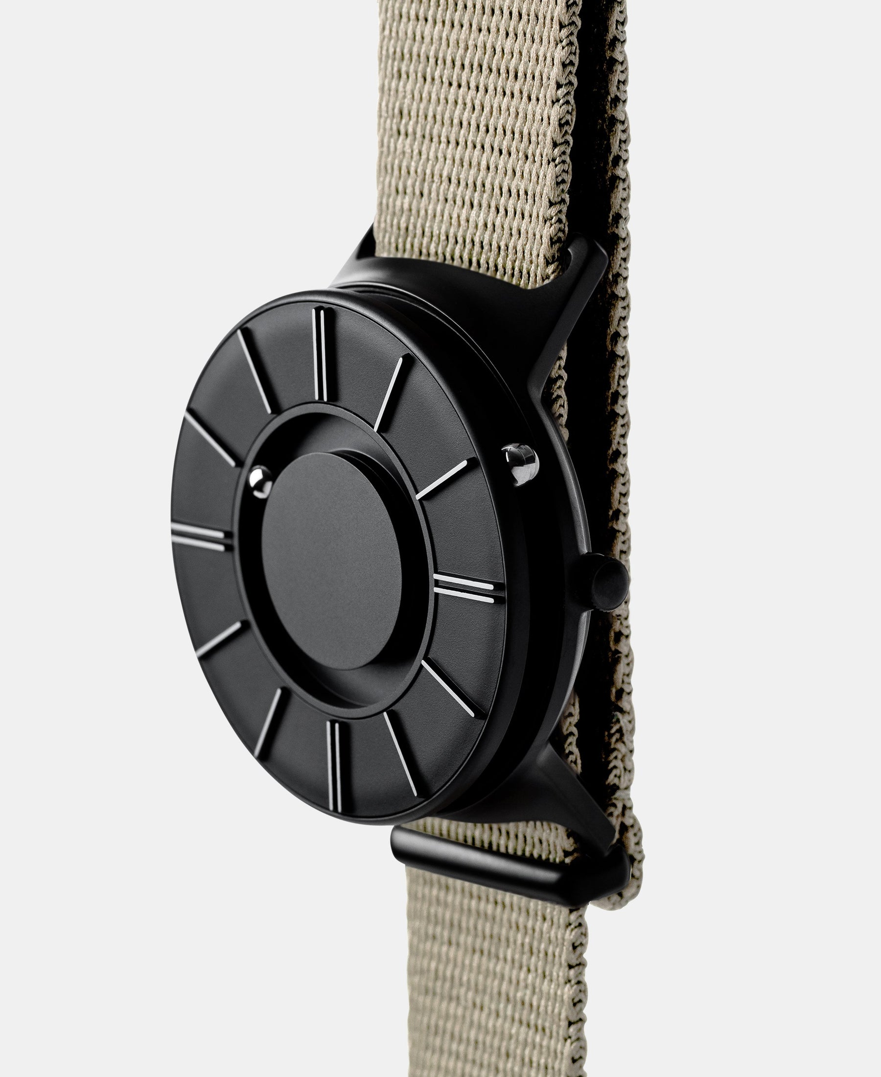 Load image into Gallery viewer, A photo of the watch from a side angle. The recessed track around the outside of the watch face is shown with the hour ball bearing in the track. The raised markers are noticeable from this perspective.