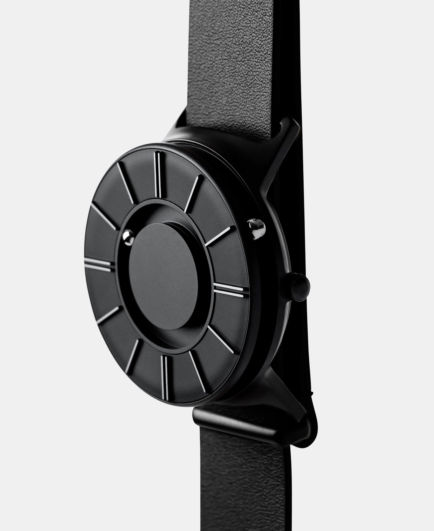Load image into Gallery viewer, A photo of the watch from a side angle. The recessed track around the outside of the watch face is shown with the hour ball bearing in the track. The raised markers are noticeable from this perspective.
