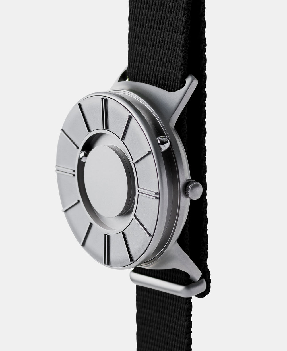 A photo of the watch from a side angle. The recessed track around the outside of the watch face is shown with the hour ball bearing in the track. The raised markers are noticeable from this perspective.