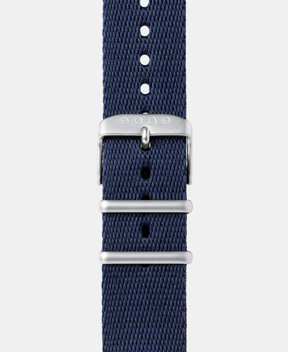 A photo shows the strap lying on a flat surface. One part has a buckle and the other part has a series of holes for an adjustable fit.