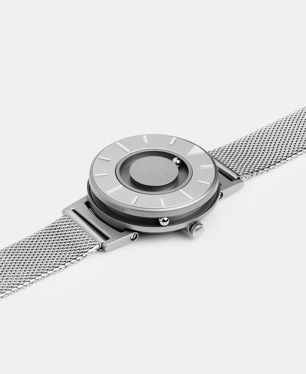 A photo of the watch lying flat on a surface. The recessed track around the outside of the watch face is shown with the hour ball bearing in the track. The raised markers are noticeable from this perspective.