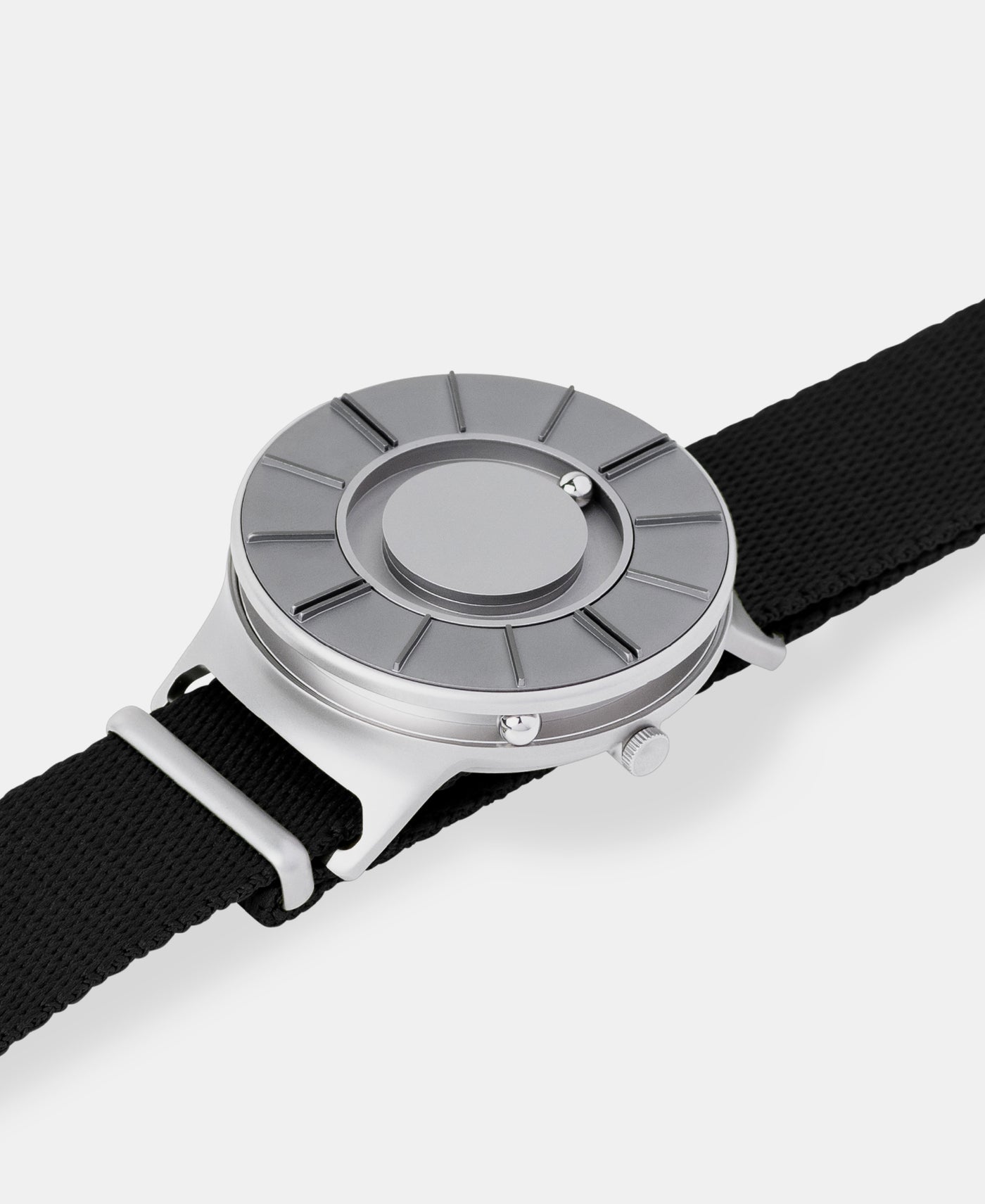 A photo of the watch lying flat on a surface. The recessed track around the outside of the watch face is shown with the hour ball bearing in the track. The raised markers are noticeable from this perspective.