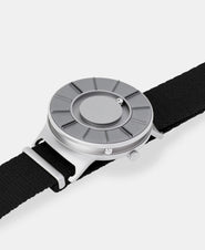 A photo of the watch lying flat on a surface. The recessed track around the outside of the watch face is shown with the hour ball bearing in the track. The raised markers are noticeable from this perspective.