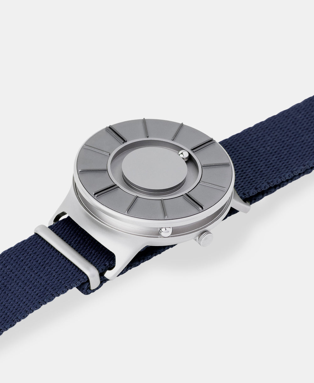 A photo of the watch lying flat on a surface. The recessed track around the outside of the watch face is shown with the hour ball bearing in the track. The raised markers are noticeable from this perspective.