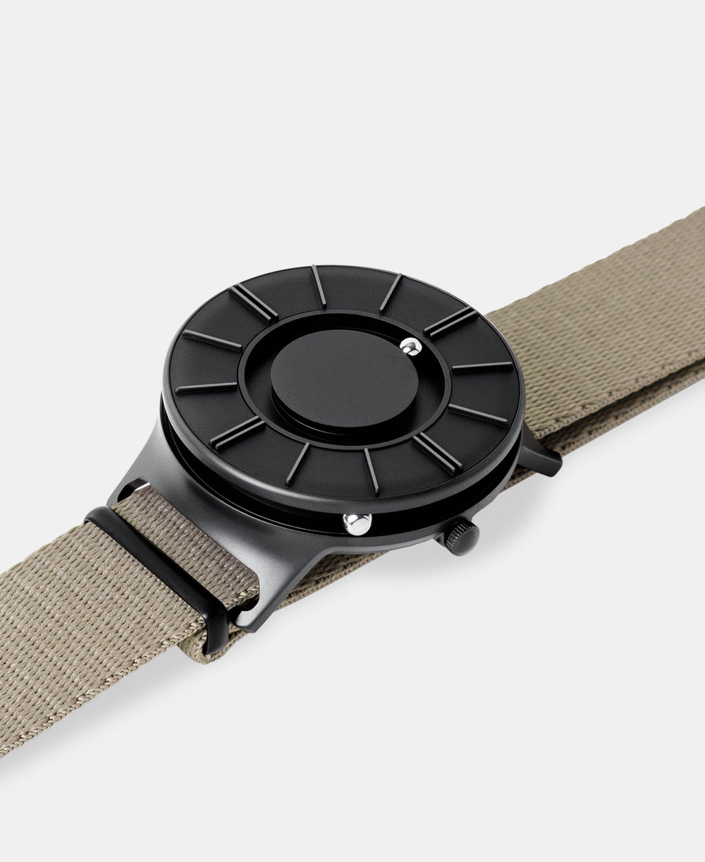 A photo of the watch lying flat on a surface. The recessed track around the outside of the watch face is shown with the hour ball bearing in the track. The raised markers are noticeable from this perspective.