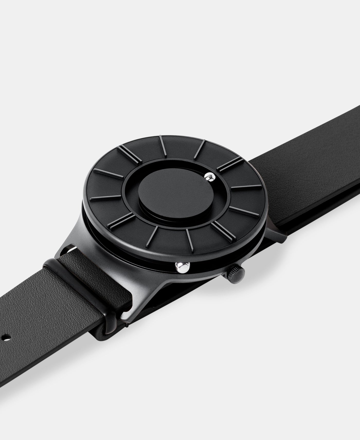 A photo of the watch lying flat on a surface. The recessed track around the outside of the watch face is shown with the hour ball bearing in the track. The raised markers are noticeable from this perspective.