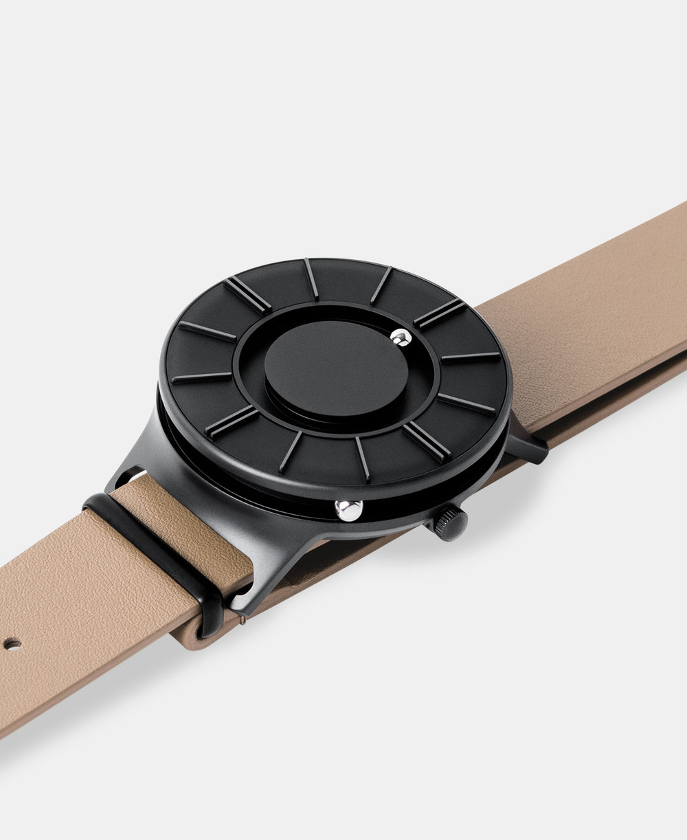 A photo of the watch lying flat on a surface. The recessed track around the outside of the watch face is shown with the hour ball bearing in the track. The raised markers are noticeable from this perspective.