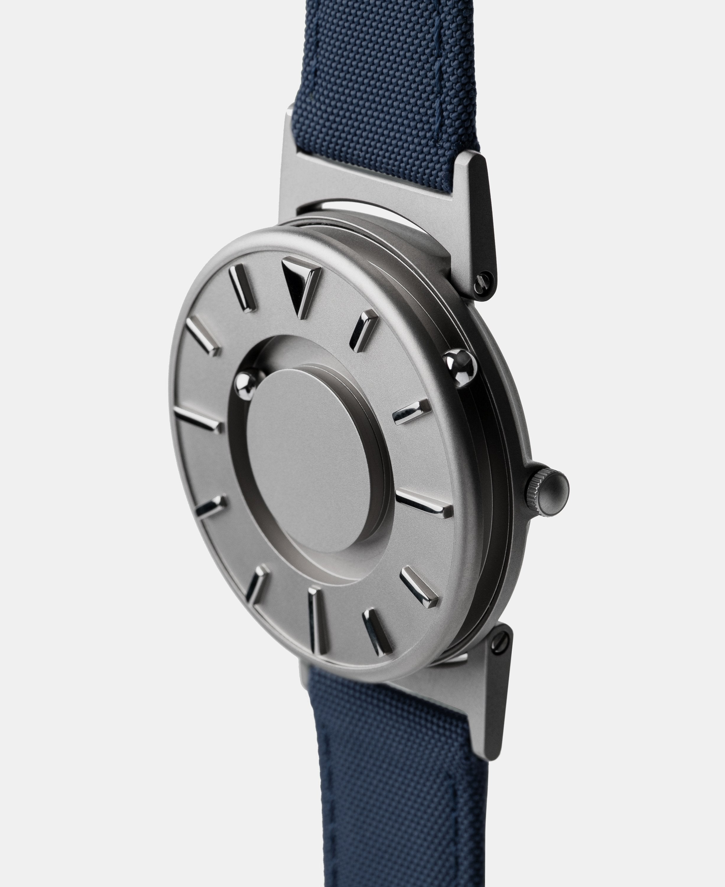 A photo of the watch from a side angle. The recessed track around the outside of the watch face is shown with the hour ball bearing in the track. The raised markers are noticeable from this perspective.