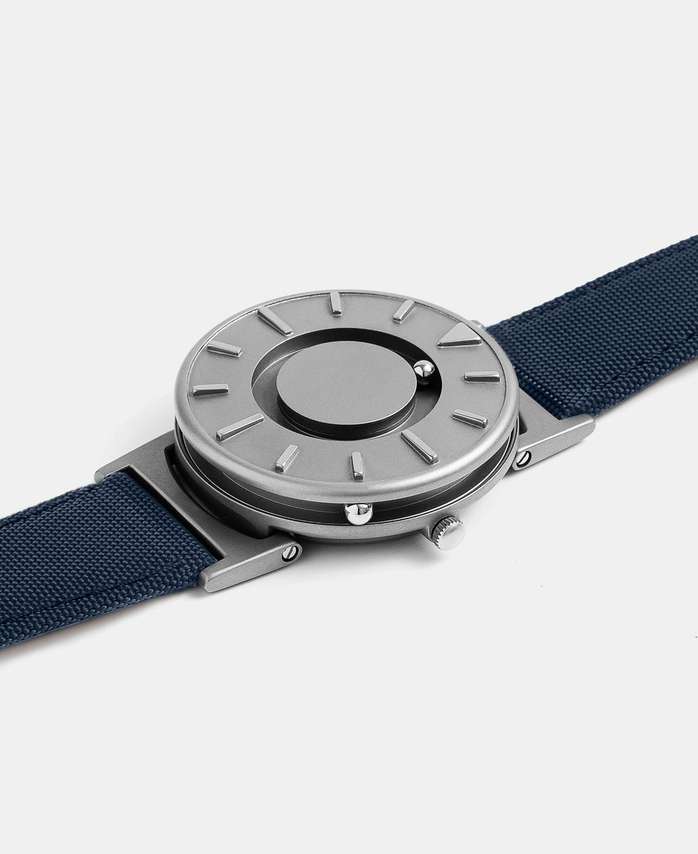 A photo of the watch lying flat on a surface. The recessed track around the outside of the watch face is shown with the hour ball bearing in the track. The raised markers are noticeable from this perspective.