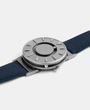 A photo of the watch lying flat on a surface. The recessed track around the outside of the watch face is shown with the hour ball bearing in the track. The raised markers are noticeable from this perspective.