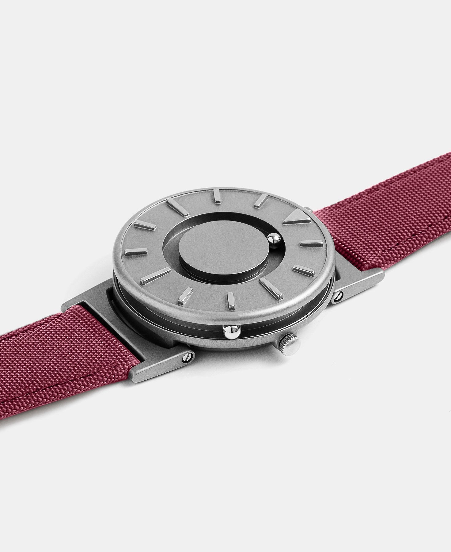 Load image into Gallery viewer, A photo of the watch lying flat on a surface. The recessed track around the outside of the watch face is shown with the hour ball bearing in the track. The raised markers are noticeable from this perspective.