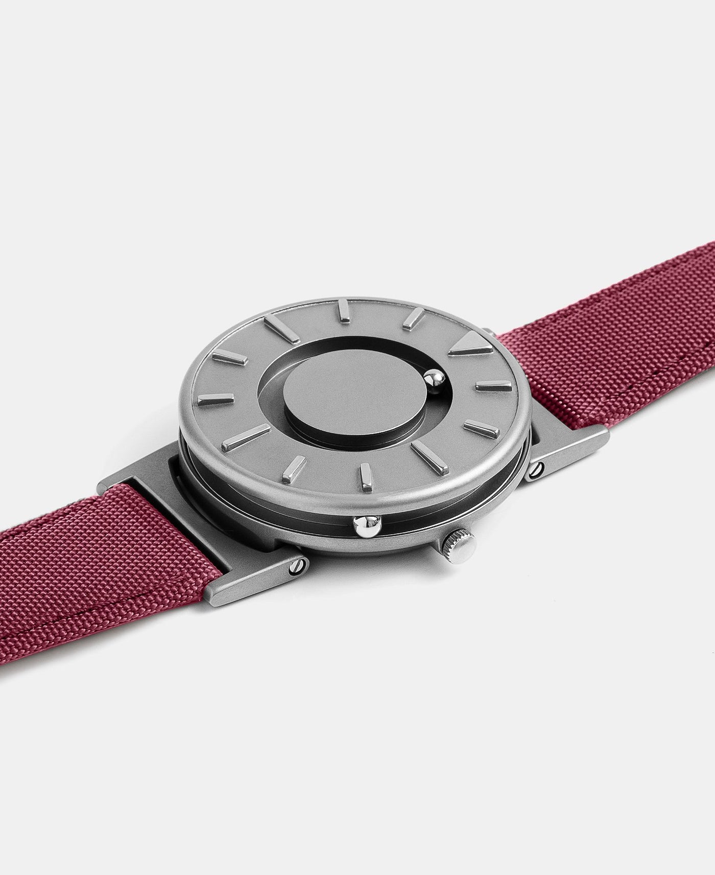 A photo of the watch lying flat on a surface. The recessed track around the outside of the watch face is shown with the hour ball bearing in the track. The raised markers are noticeable from this perspective.