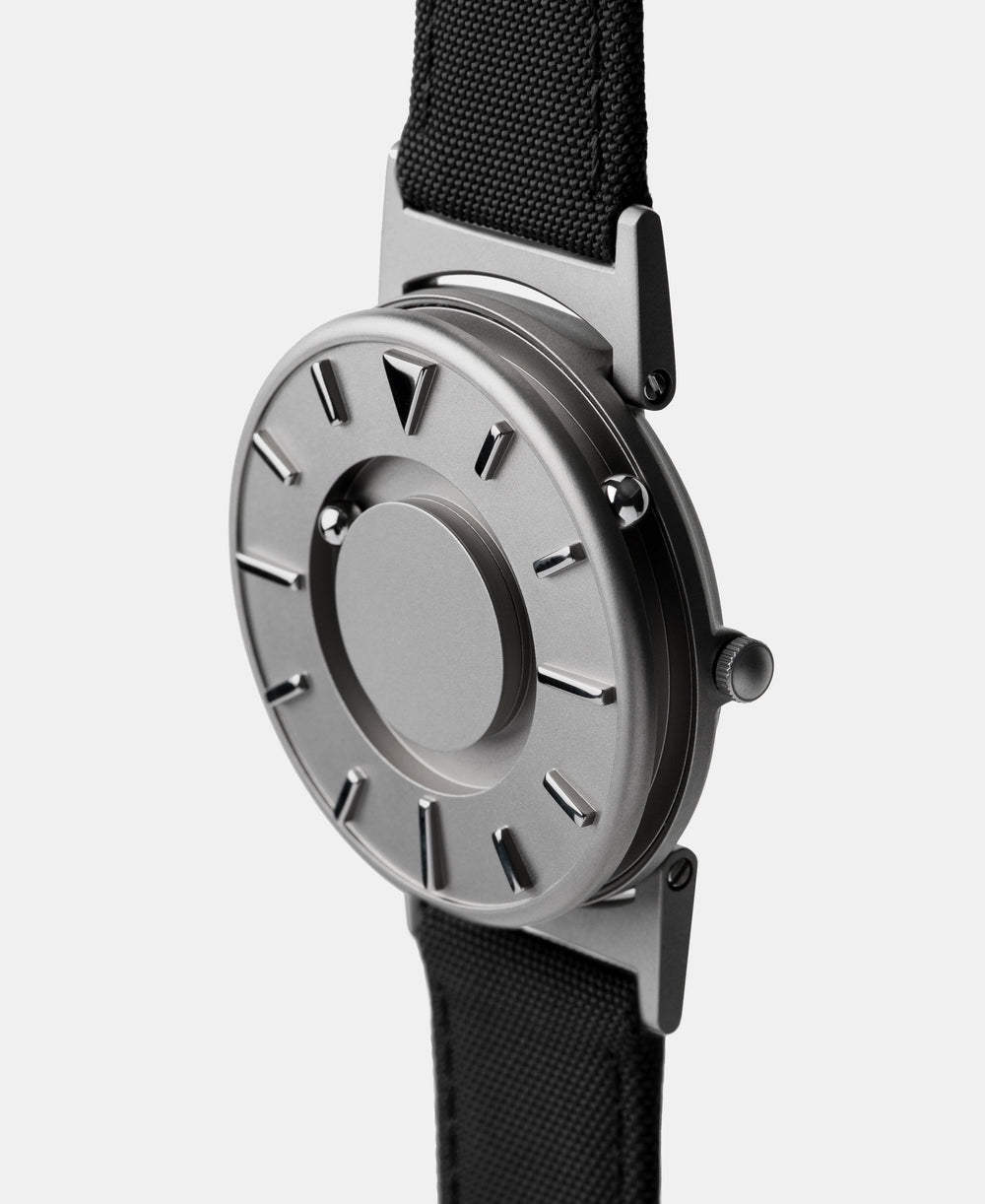 A photo of the watch from a side angle. The recessed track around the outside of the watch face is shown with the hour ball bearing in the track. The raised markers are noticeable from this perspective.