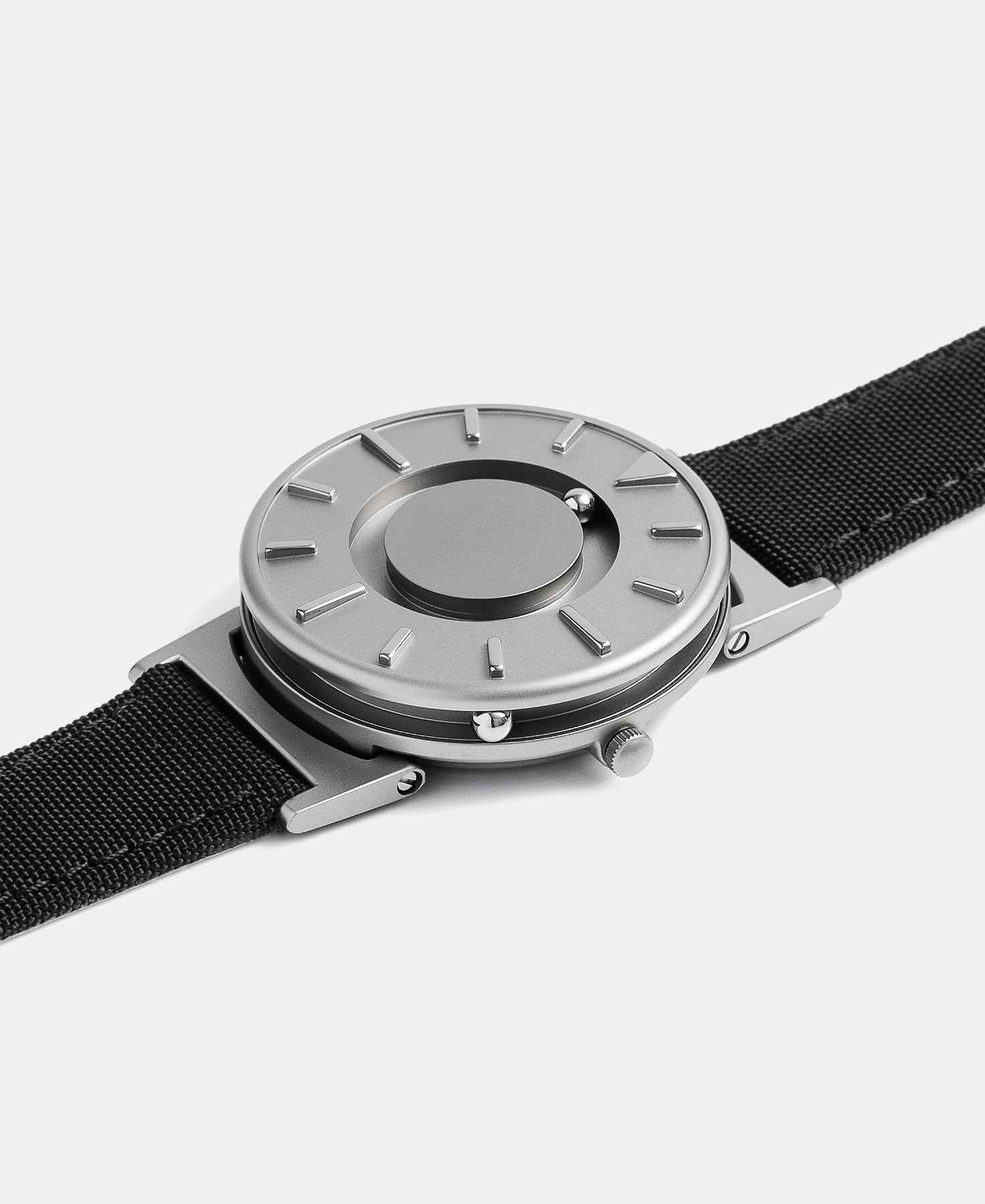 Load image into Gallery viewer, A photo of the watch lying flat on a surface. The recessed track around the outside of the watch face is shown with the hour ball bearing in the track. The raised markers are noticeable from this perspective.