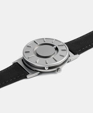 A photo of the watch lying flat on a surface. The recessed track around the outside of the watch face is shown with the hour ball bearing in the track. The raised markers are noticeable from this perspective.