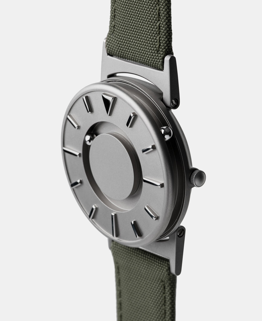 A photo of the watch from a side angle. The recessed track around the outside of the watch face is shown with the hour ball bearing in the track. The raised markers are noticeable from this perspective.