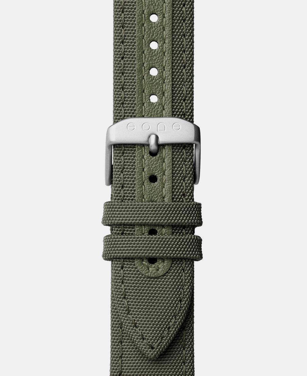 A photo shows the strap lying on a flat surface. One part has a buckle and the other part has a series of holes for an adjustable fit.