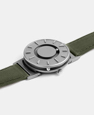 A photo of the watch lying flat on a surface. The recessed track around the outside of the watch face is shown with the hour ball bearing in the track. The raised markers are noticeable from this perspective.
