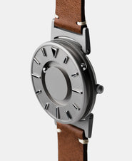 A photo of the watch from a side angle. The recessed track around the outside of the watch face is shown with the hour ball bearing in the track. The raised markers are noticeable from this perspective.