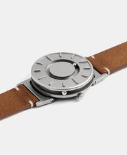 A photo of the watch lying flat on a surface. The recessed track around the outside of the watch face is shown with the hour ball bearing in the track. The raised markers are noticeable from this perspective.