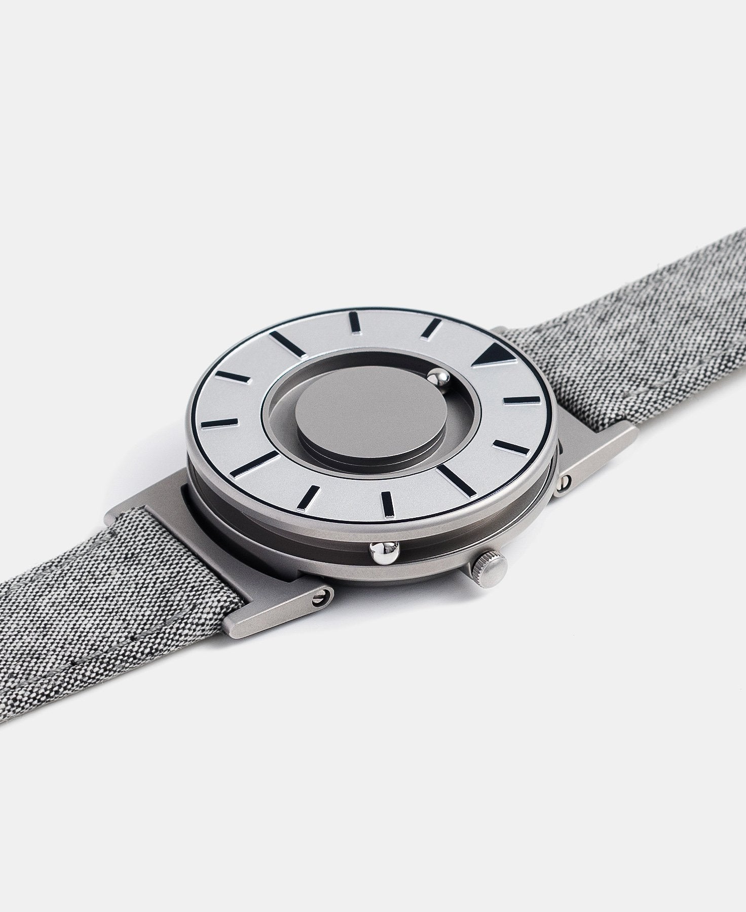 Load image into Gallery viewer, A photo of the watch lying flat on a surface. The recessed track around the outside of the watch face is shown with the hour ball bearing in the track. The raised markers are noticeable from this perspective.