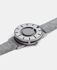 A photo of the watch lying flat on a surface. The recessed track around the outside of the watch face is shown with the hour ball bearing in the track. The raised markers are noticeable from this perspective.