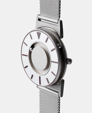 A photo of the watch from a side angle. The recessed track around the outside of the watch face is shown with the hour ball bearing in the track. The raised markers are noticeable from this perspective.