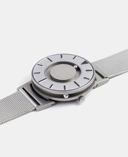 A photo of the watch lying flat on a surface. The recessed track around the outside of the watch face is shown with the hour ball bearing in the track. The raised markers are noticeable from this perspective.