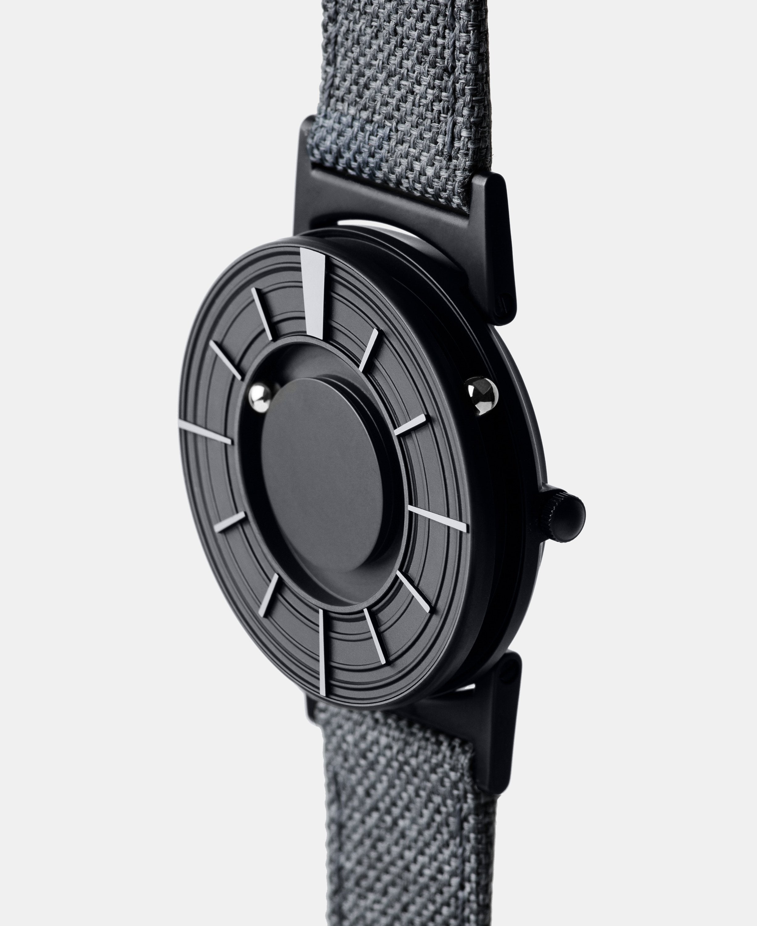 A photo of the watch from a side angle. The recessed track around the outside of the watch face is shown with the hour ball bearing in the track. The raised markers are noticeable from this perspective.