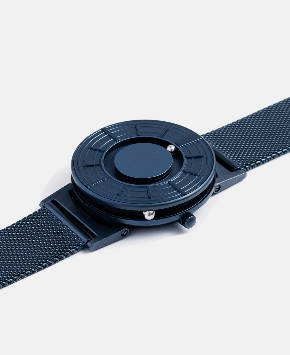 A photo of the watch lying flat on a surface. The recessed track around the outside of the watch face is shown with the hour ball bearing in the track. The raised markers are noticeable from this perspective.