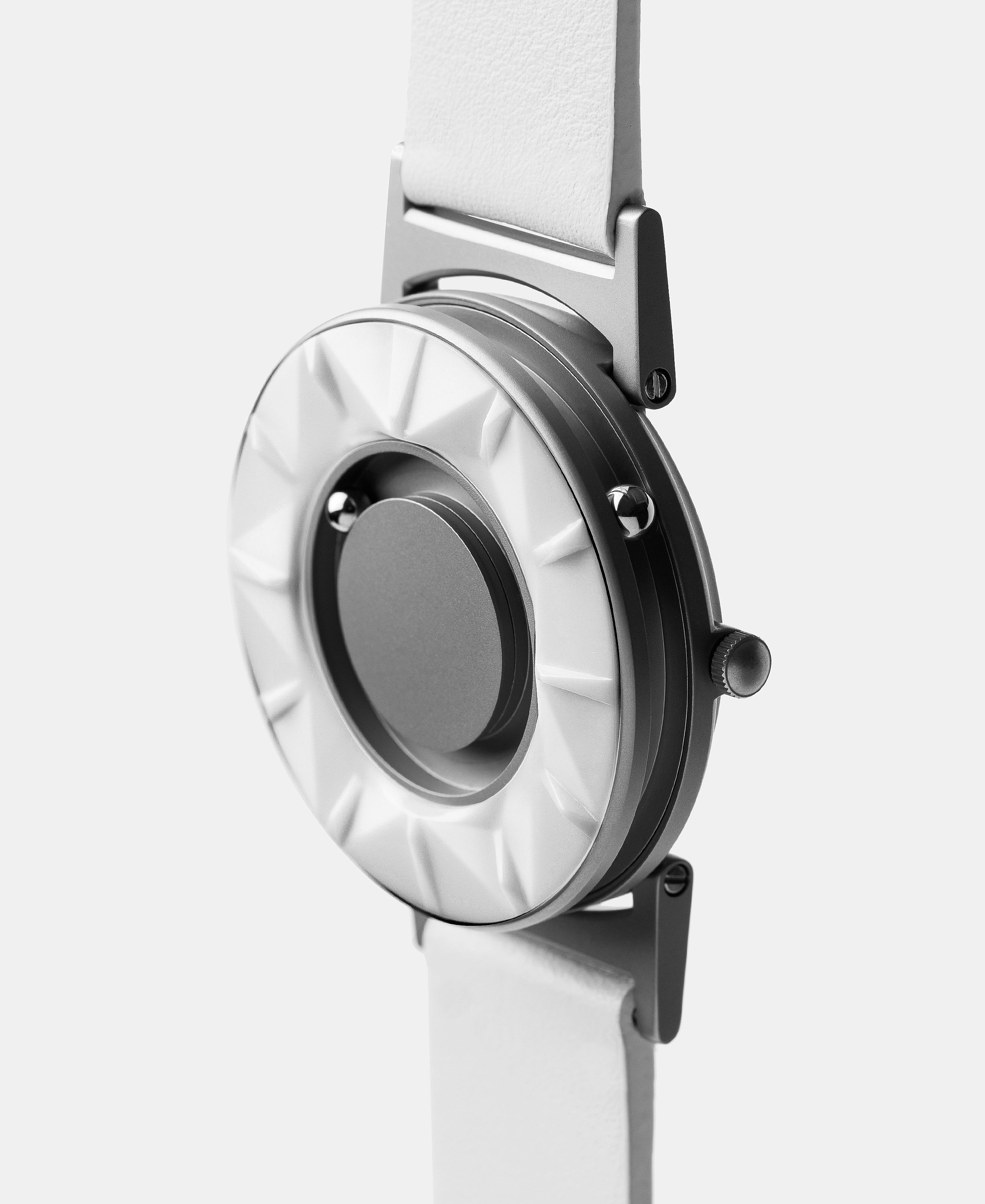 A photo of the watch from a side angle. The recessed track around the outside of the watch face is shown with the hour ball bearing in the track. The raised markers are noticeable from this perspective.