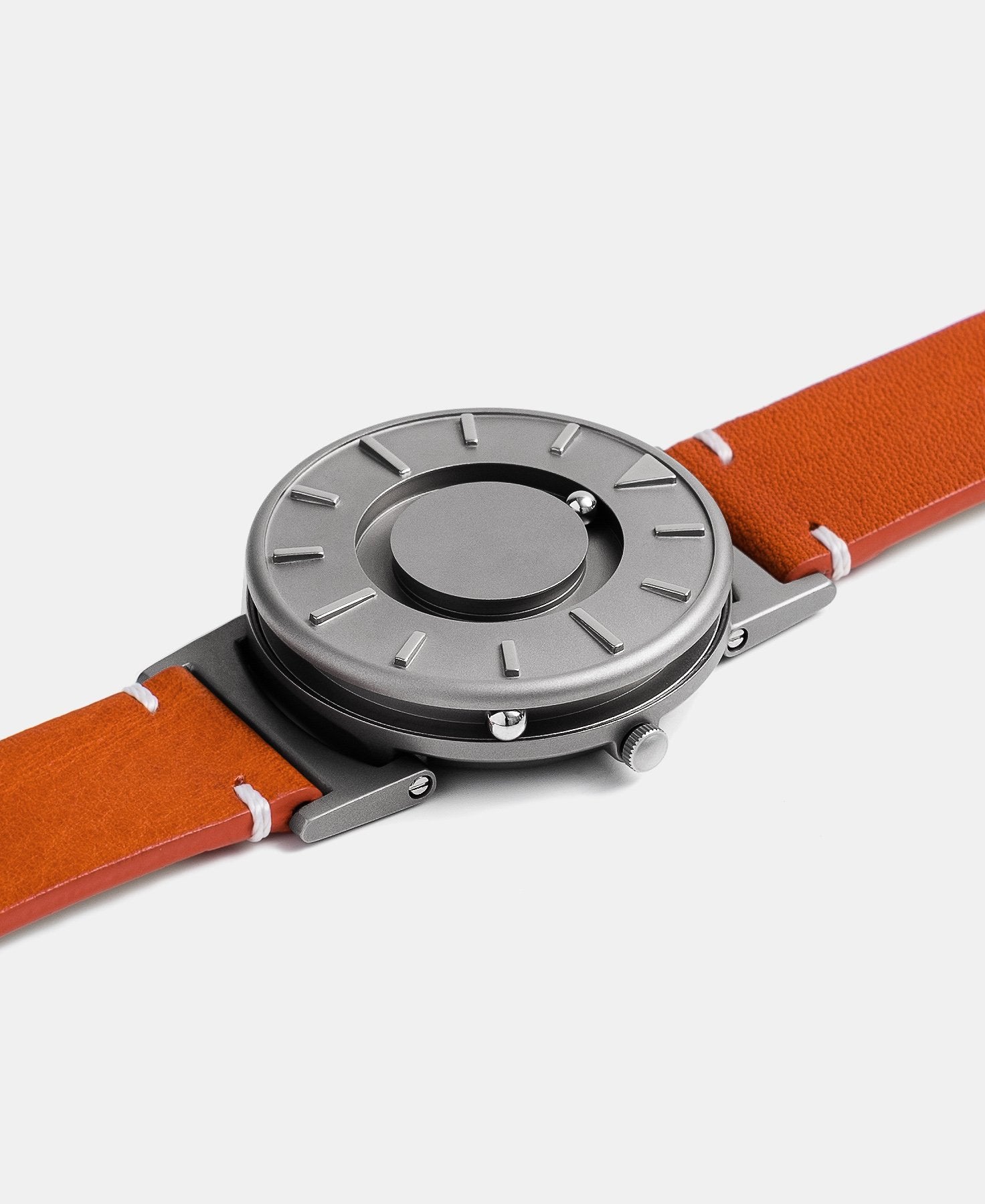 Load image into Gallery viewer, A photo of the watch lying flat on a surface. The recessed track around the outside of the watch face is shown with the hour ball bearing in the track. The raised markers are noticeable from this perspective.