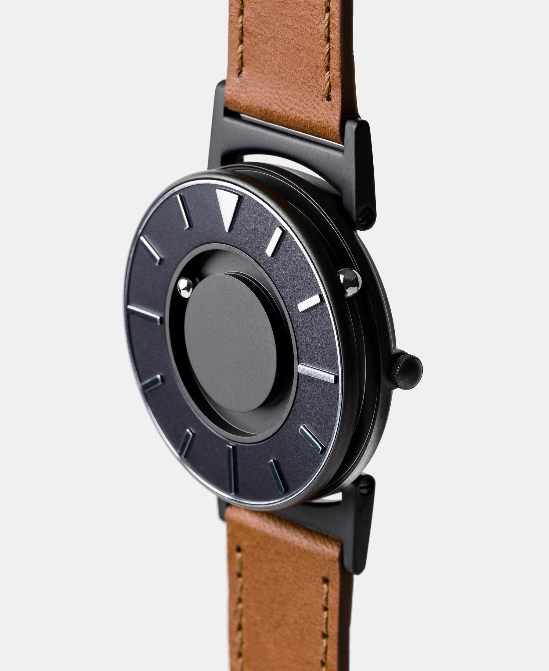 Load image into Gallery viewer, A photo of the watch from a side angle. The recessed track around the outside of the watch face is shown with the hour ball bearing in the track. The raised markers are noticeable from this perspective.